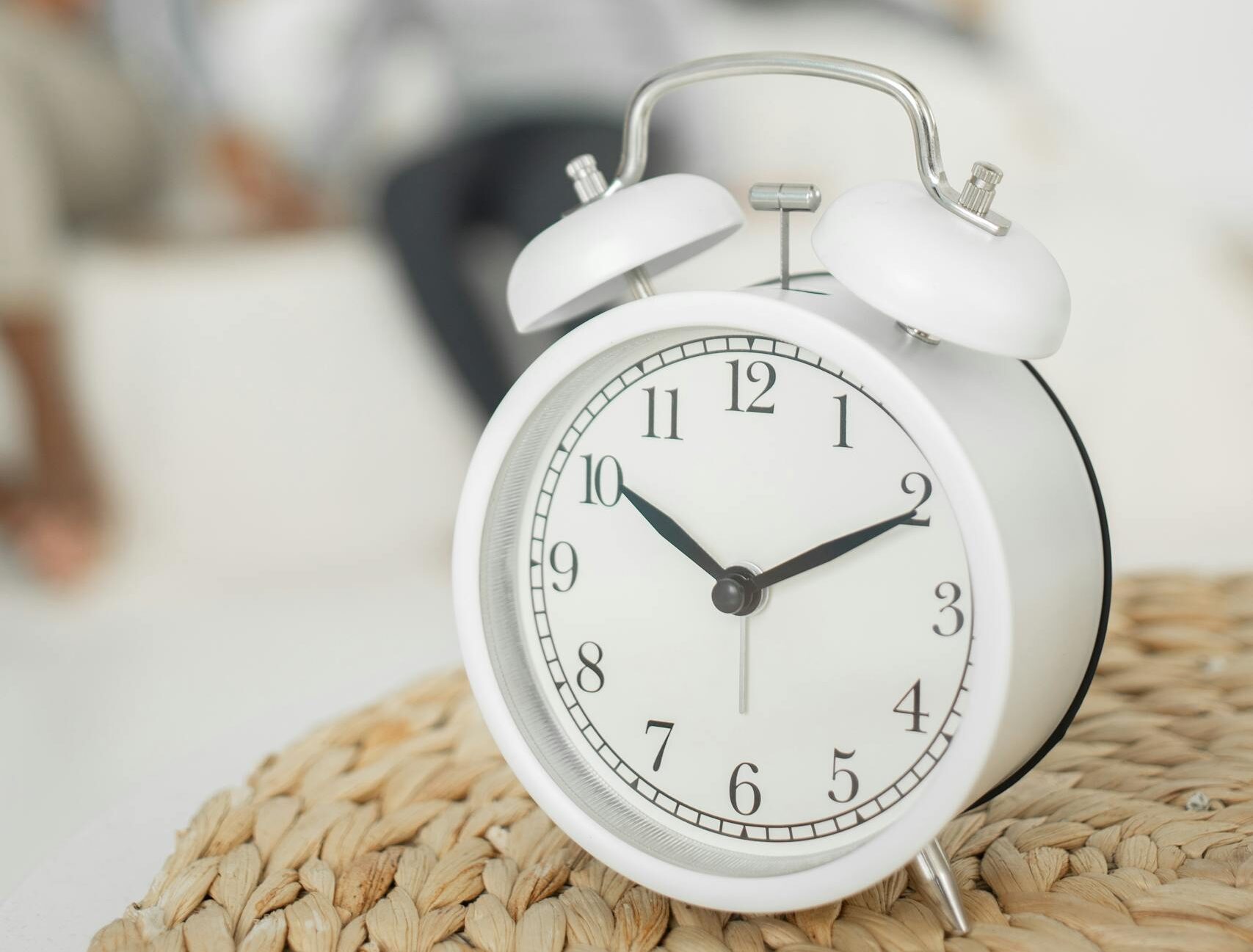 Alarm clock placed on table in bedroom near child playing with mother