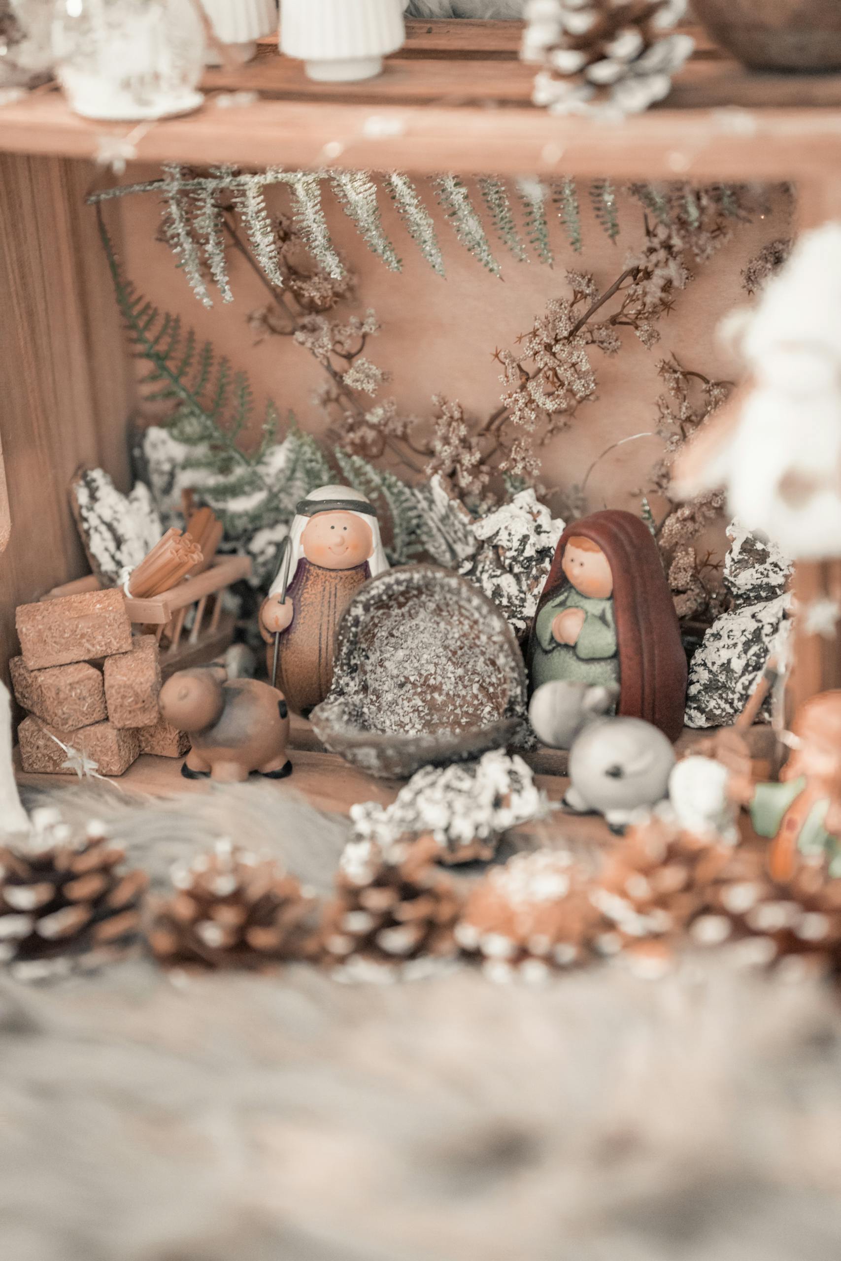 Delicate close-up of an artisan-crafted nativity scene surrounded by pine cones and natural accents.