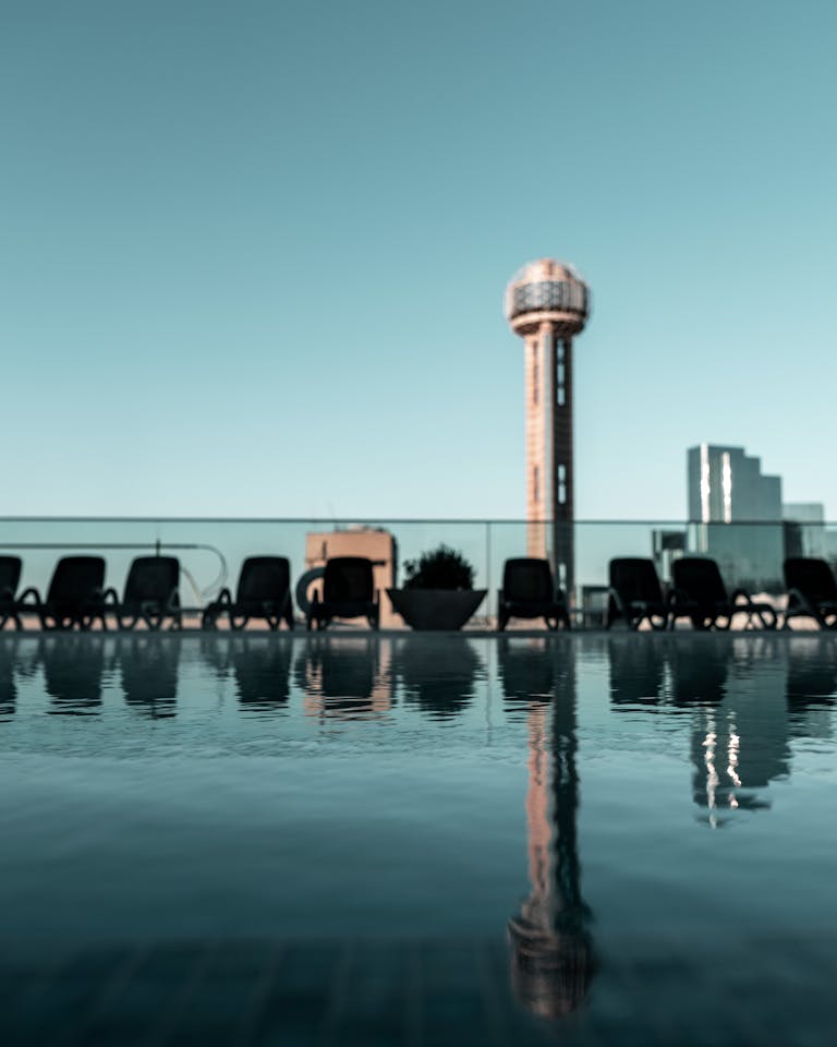 Cityscape featuring a tower, pool, and skyscrapers reflecting the modern urban vibe.
